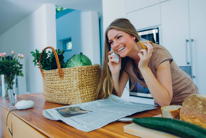 Woman with VoIP home phone to her ear leaning on kitchen counter